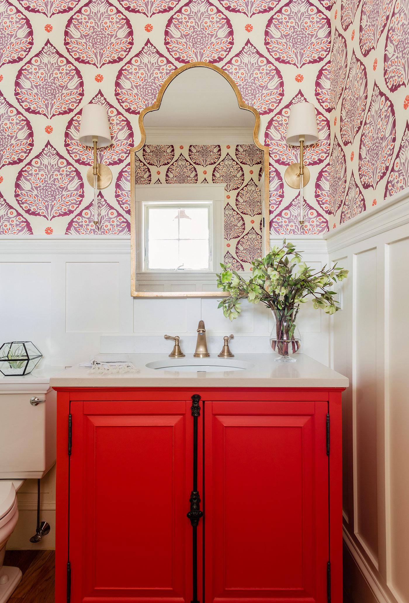 色彩缤纷的化妆室，红色的橱柜门和白色的镶板墙