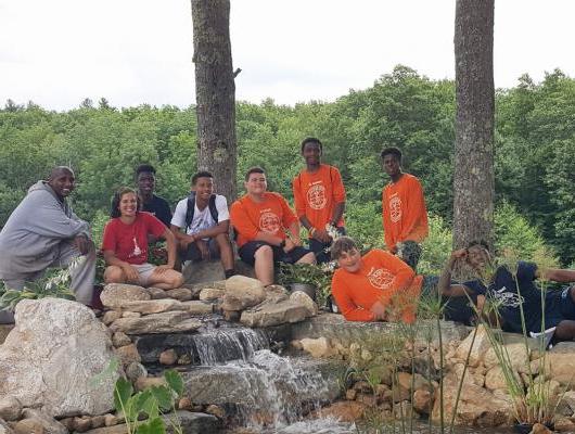 Magma Design Group at Ron Burton Training Village with a group of kids sitting at a waterfall